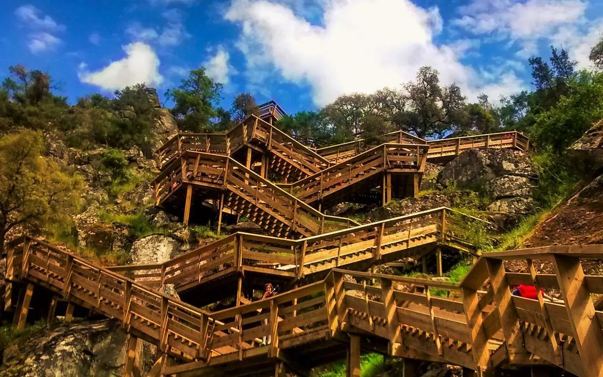 Wooden stairways and walkways zigzagging up a rocky hillside under a blue sky